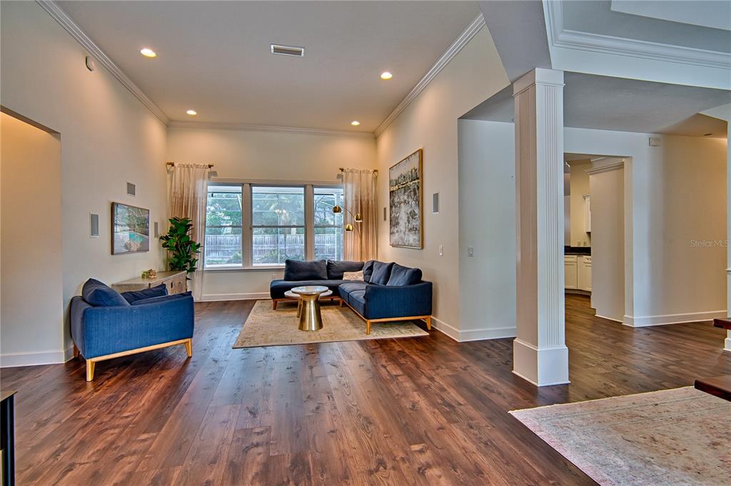 A living room features dark wood floors, blue sectional seating, and a large window — 9244 SW 31ST PLACE, GAINESVILLE, FL