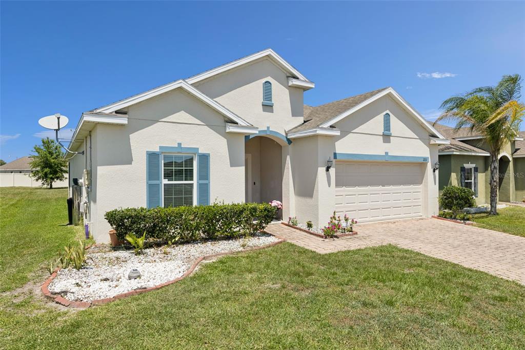 A single-story suburban house with a beige stucco exterior, blue shutters, and a paved driveway — 2211 RIVERGLEN COURT, KISSIMMEE, FL