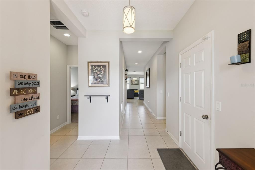 A bright entryway with tile flooring leads down a hallway toward a living area — 2211 RIVERGLEN COURT, KISSIMMEE, FL
