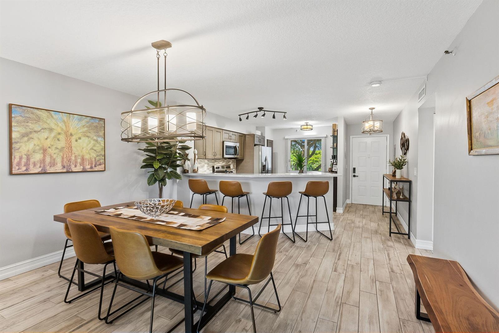An open-concept dining area and kitchen feature wood-look tile floors and leather bar stools — 2215 Cypress Island Drive # 301, Pompano Beach FL 33069, POMPANO BEACH, FL