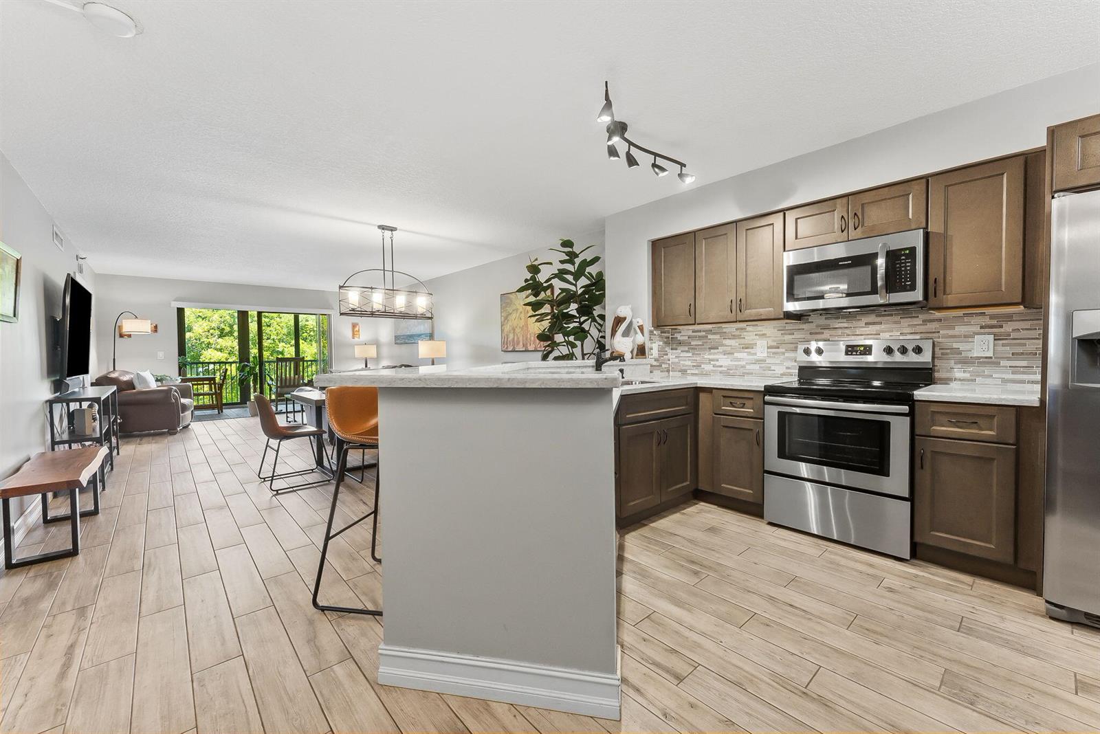 A kitchen with brown cabinets and stainless steel appliances opens into a living area — 2215 Cypress Island Drive # 301, Pompano Beach FL 33069, POMPANO BEACH, FL