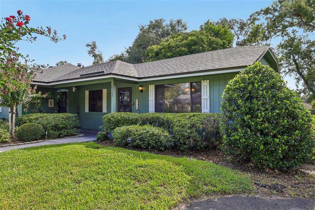 A single-story house with green siding, a shingled roof, and a large front hedge — 632 MOUNT HOMER ROAD UNIT 4A, EUSTIS, FL