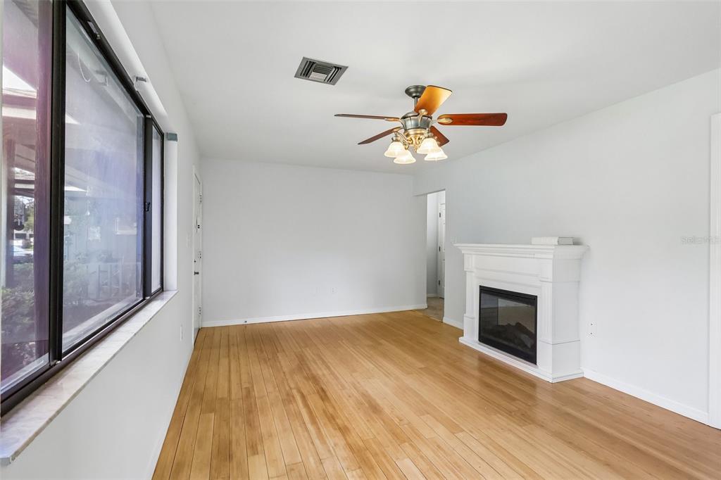 A living room with light wood floors, a white fireplace, and a ceiling fan — 632 MOUNT HOMER ROAD UNIT 4A, EUSTIS, FL