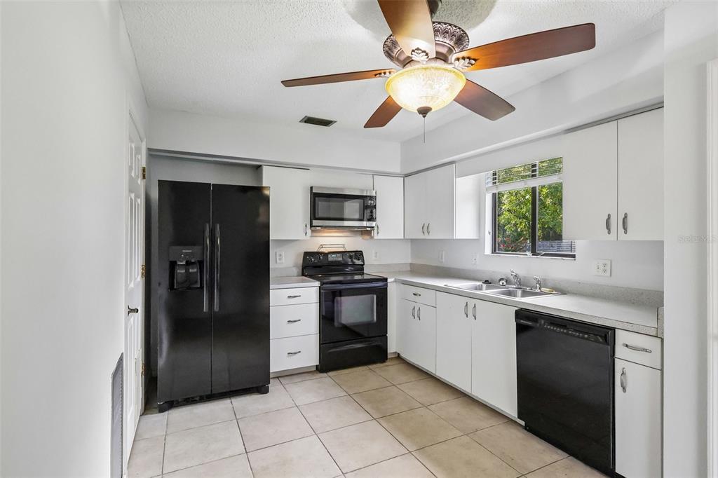 A kitchen with white cabinets, black appliances, tile flooring, and a ceiling fan — 632 MOUNT HOMER ROAD UNIT 4A, EUSTIS, FL