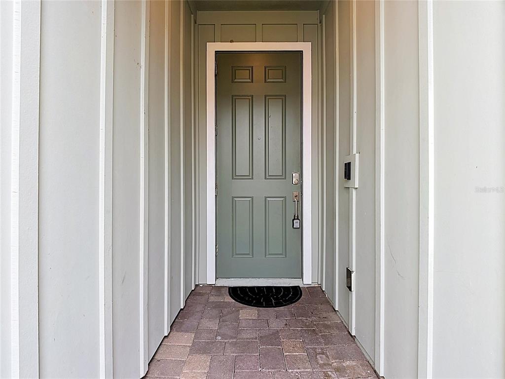 A green front door with a lockbox sits at the end of a paved entryway — 2920 TITLE STREET, KISSIMMEE, FL