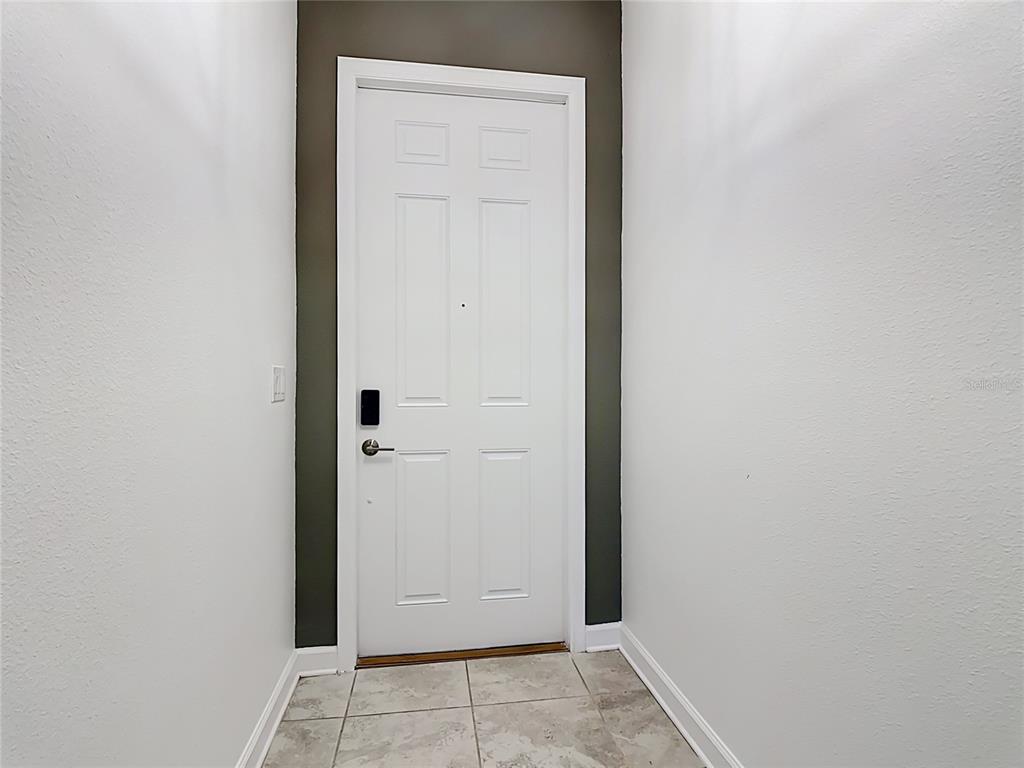 A white door with a smart lock is centered against a dark accent wall — 2920 TITLE STREET, KISSIMMEE, FL