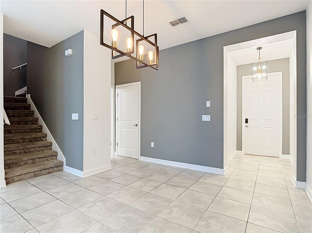 An entryway features tile flooring, gray walls, a staircase, and a modern rectangular pendant light — 2920 TITLE STREET, KISSIMMEE, FL