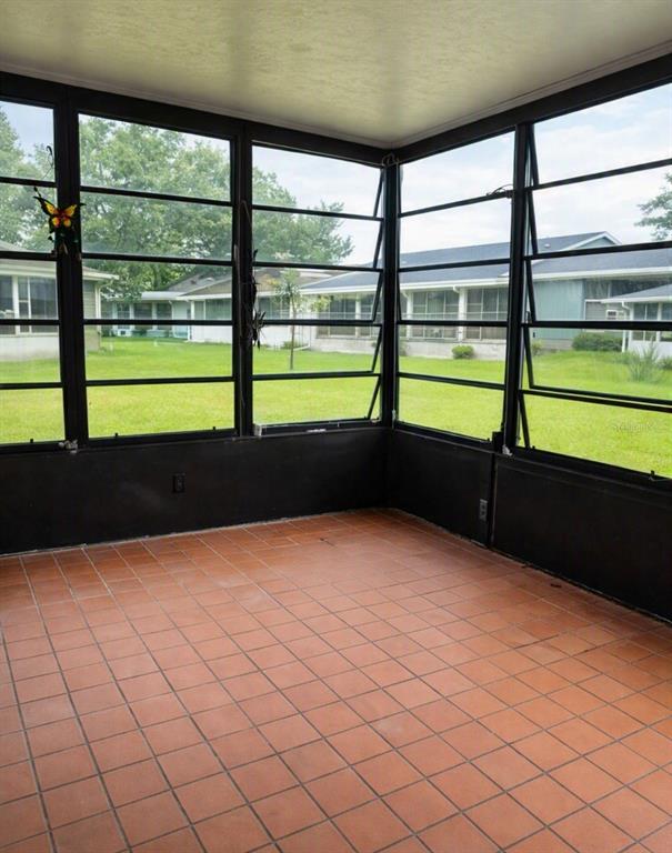 A sunroom with terracotta tile flooring and large windows overlooking a grassy backyard — 1412 PORTOBELLO DRIVE, PORT ORANGE, FL