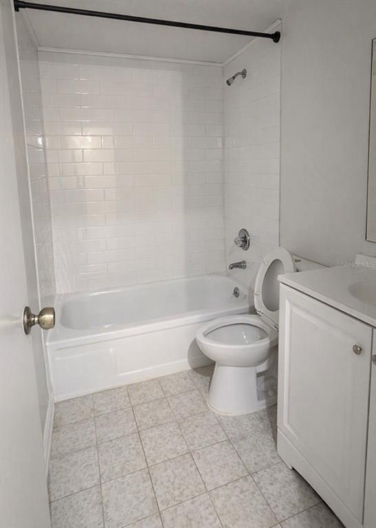 A bathroom features a white bathtub with subway tile walls, a toilet, and a vanity — 1412 PORTOBELLO DRIVE, PORT ORANGE, FL