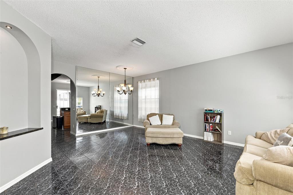 A living room features dark marble-patterned tile flooring, a mirrored wall, and a chandelier — 514 GREG STREET, VALRICO, FL