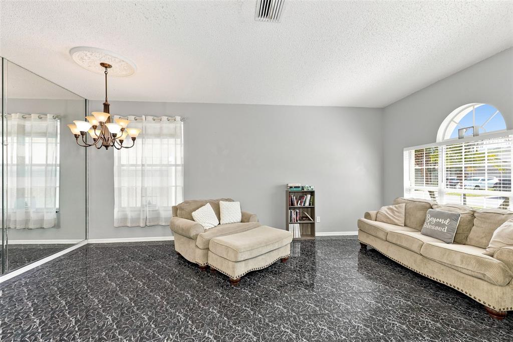 A living room features dark marble-patterned tile floors, a chandelier, and beige upholstered furniture — 514 GREG STREET, VALRICO, FL