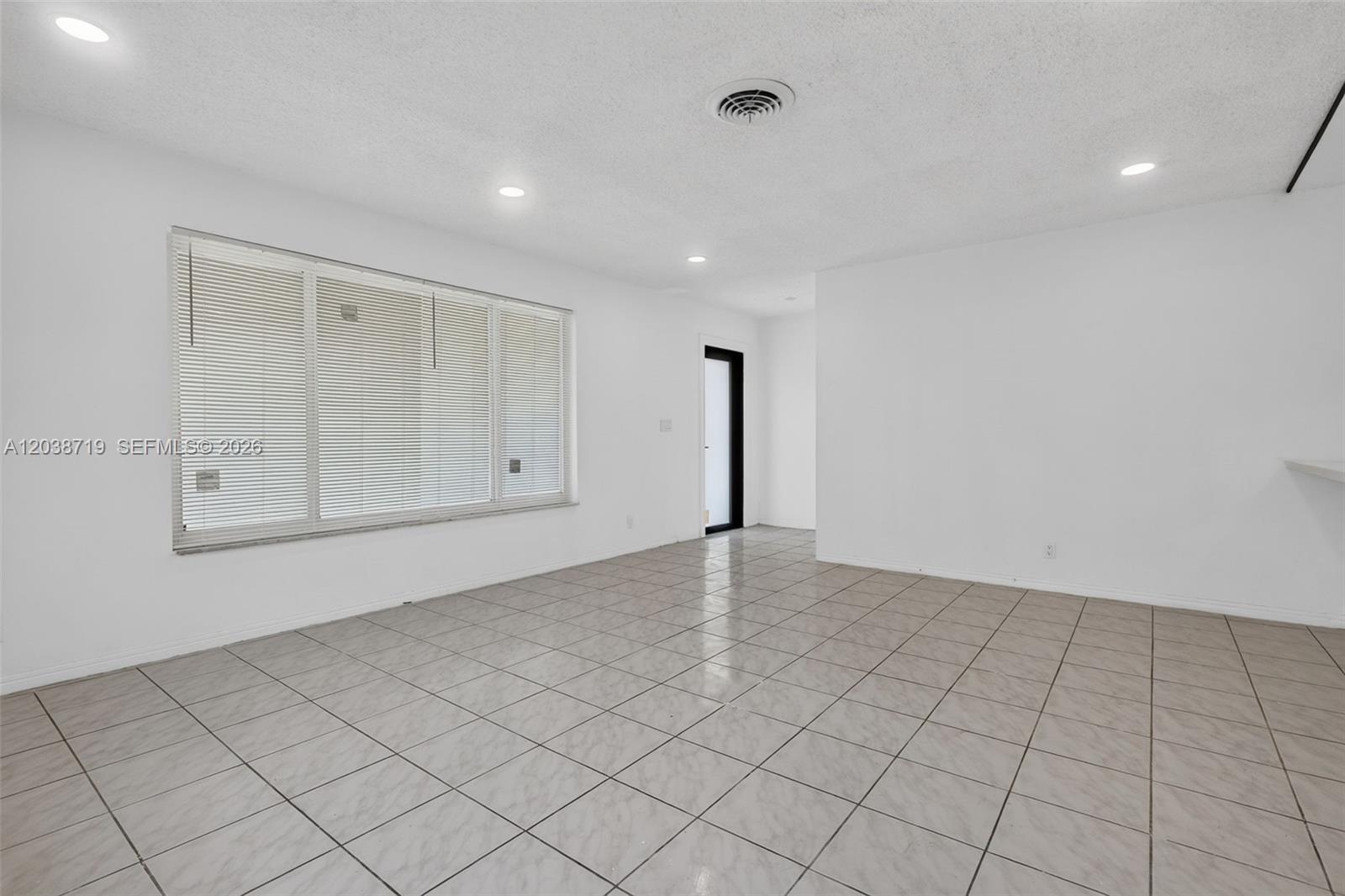 An empty room features white walls, recessed lighting, a large window with blinds, and tiled floors — 258 SW 8th St, Dania Beach FL 33004, DANIA BEACH, FL
