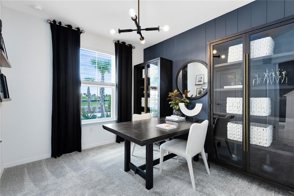 A home office features a dark wood desk, two chairs, and a dark blue accent wall — 1147 LEMONGRASS ALLEY, ORLANDO, FL