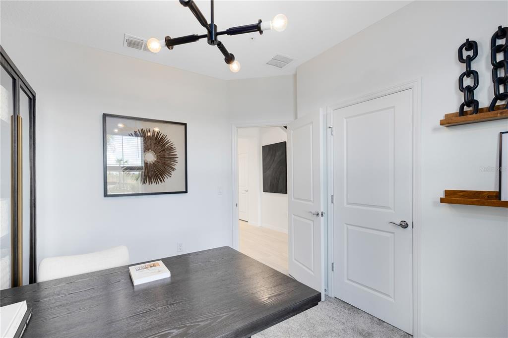 A home office features a dark wooden desk, a modern light fixture, and white doors — 1147 LEMONGRASS ALLEY, ORLANDO, FL