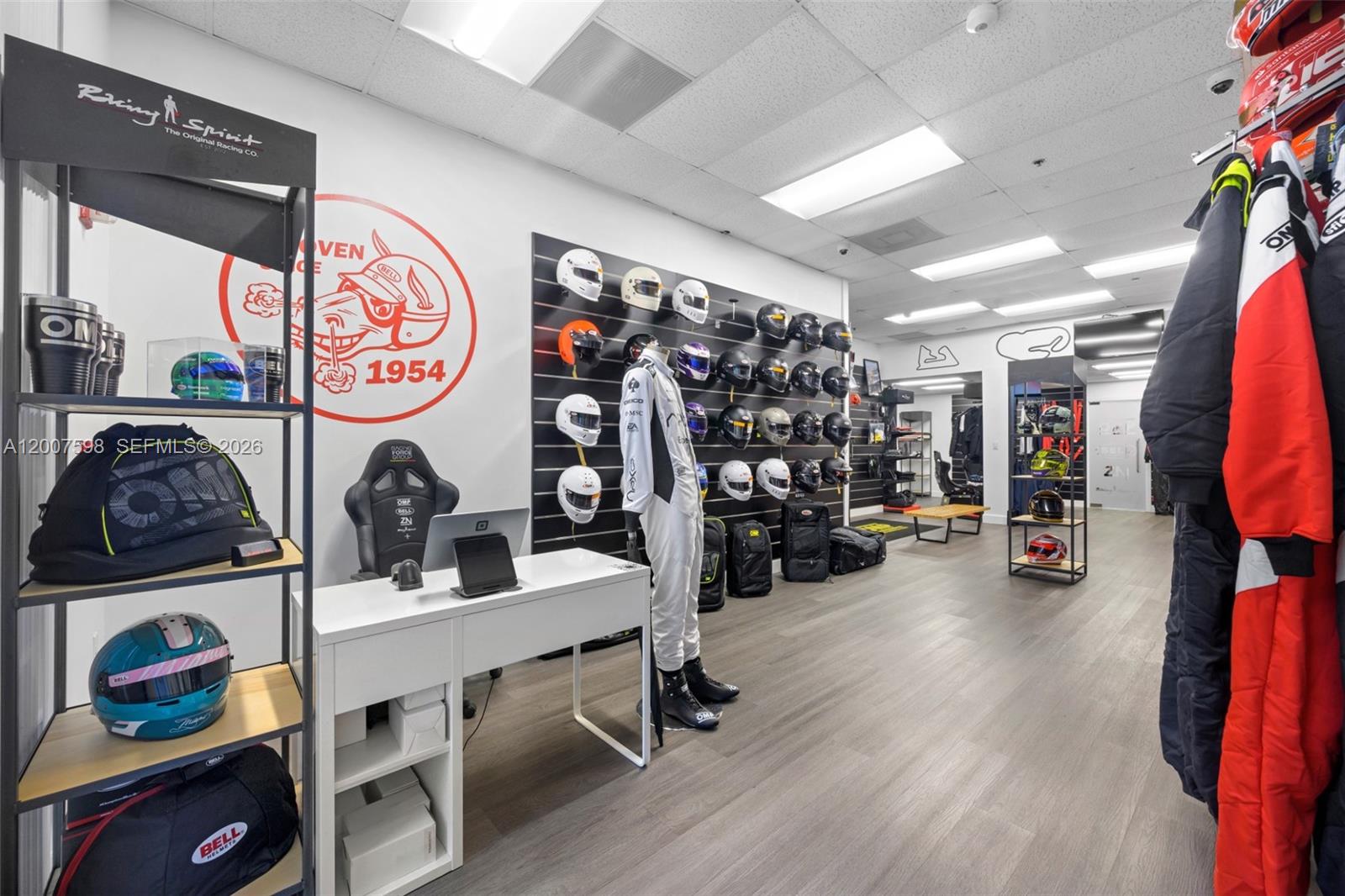 A retail store displays racing helmets, apparel, and gear on shelves and wall-mounted racks — DORAL, FL