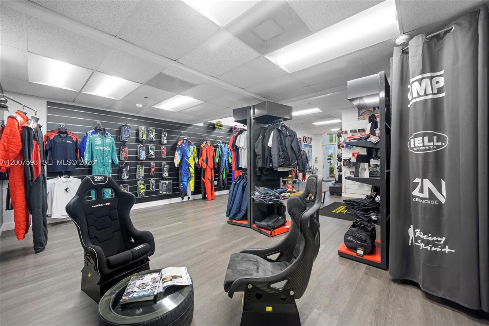 A retail store displays racing gear, apparel, and bucket seats on a wood-look floor — DORAL, FL