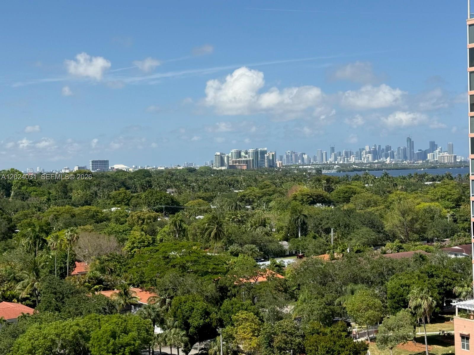 A high-angle view shows a lush green landscape with a distant city skyline — 90 Edgewater Dr # 1222, Coral Gables FL 33133, CORAL GABLES, FL