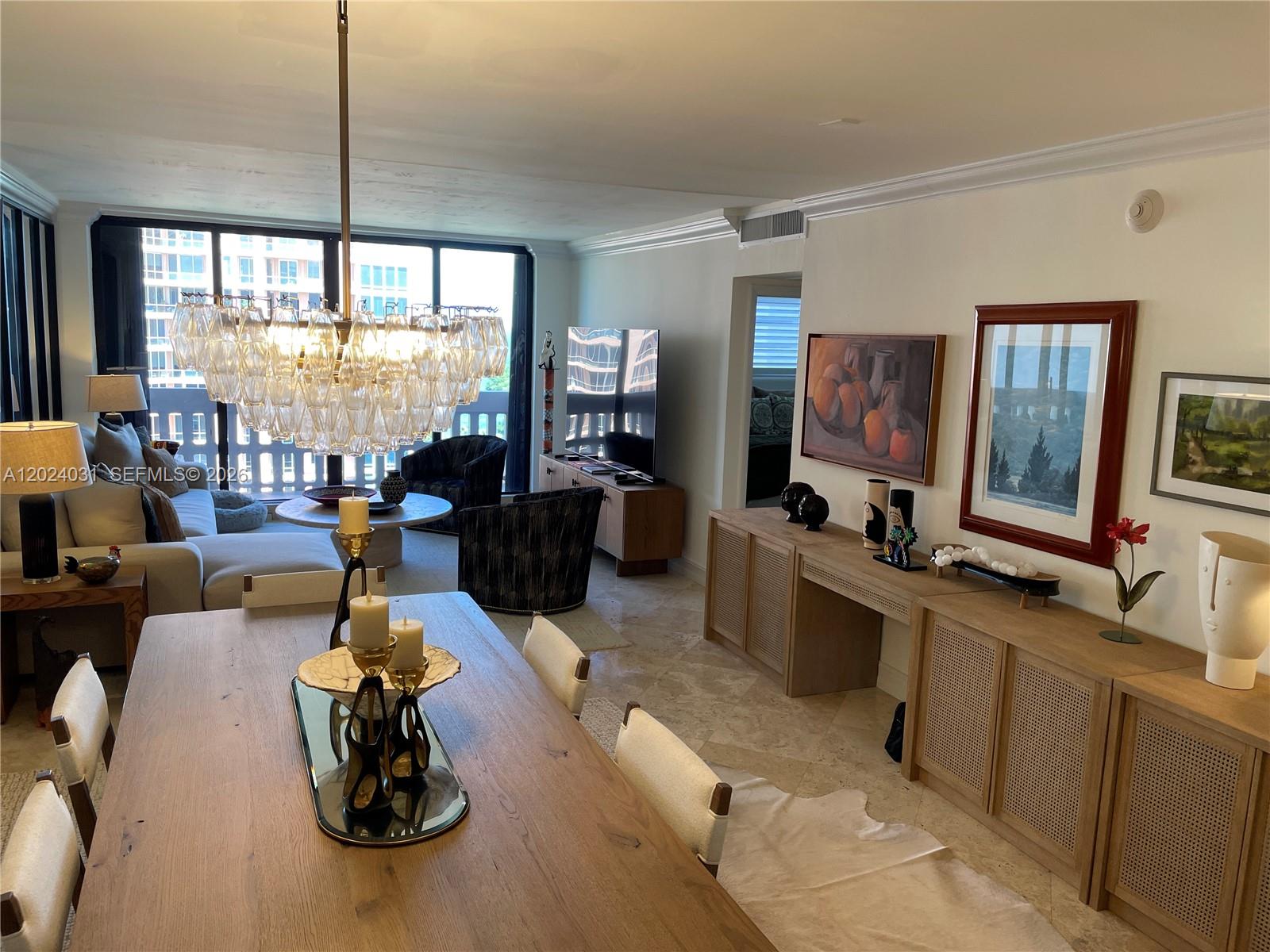 A dining area with a large chandelier leads into a living room with floor-to-ceiling windows — 90 Edgewater Dr # 1222, Coral Gables FL 33133, CORAL GABLES, FL