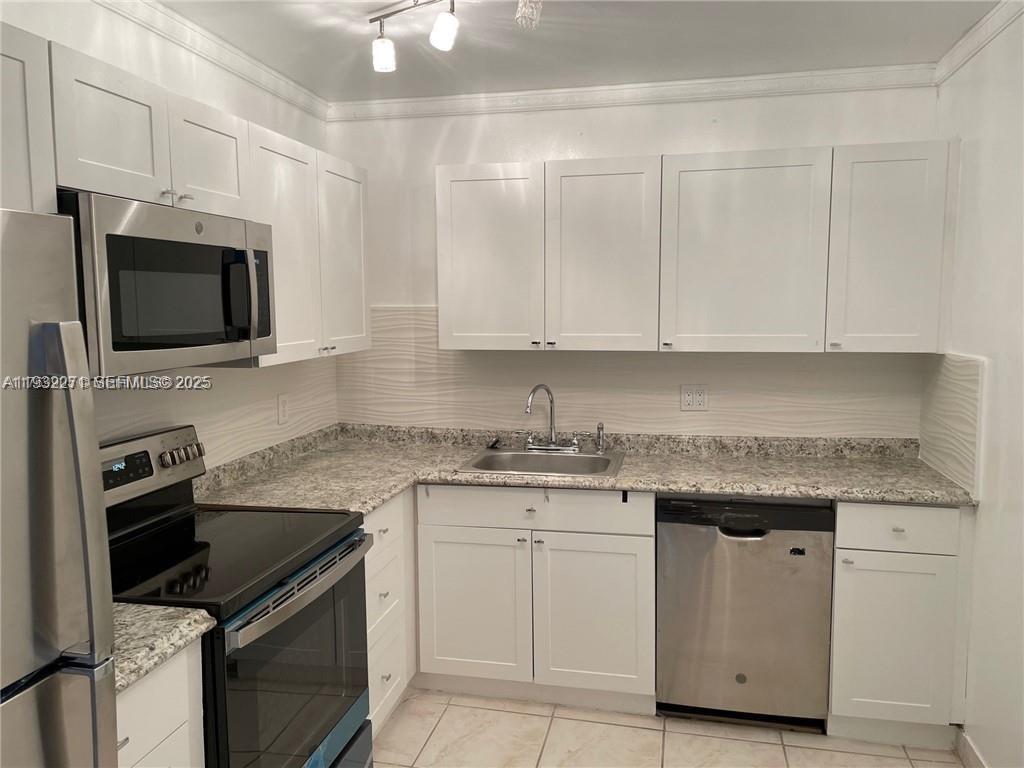 A kitchen features white cabinets, granite countertops, stainless steel appliances, and a tiled floor — 2500 Parkview Dr # 1920, Hallandale Beach FL 33009, HALLANDALE BEACH, FL