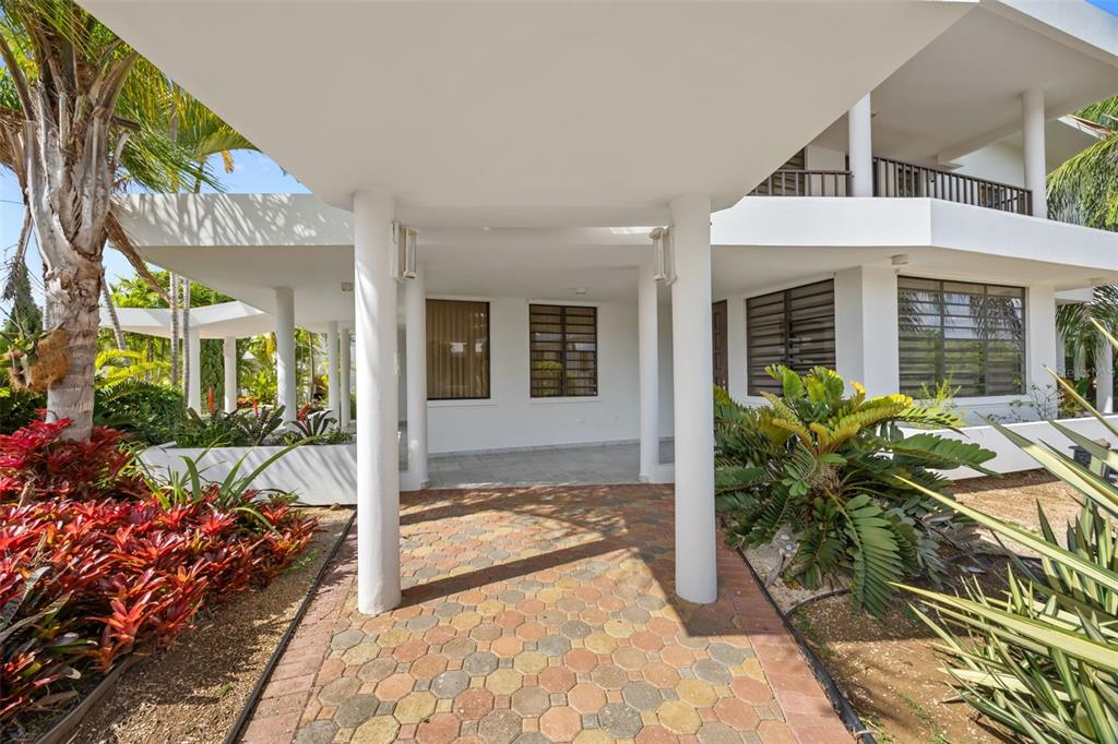 A paved walkway leads to the covered entrance of a white multi-story house with landscaping — 3 CARLOTA STREET, GUAYAMA, PR