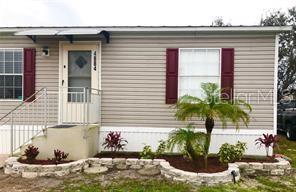 A single-story house with light siding, red shutters, a front door, and a stone garden bed — 4884 DUNCAN ROAD, PUNTA GORDA, FL