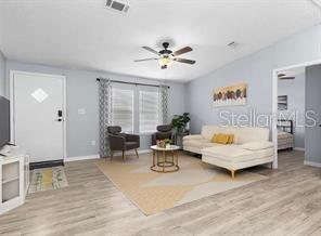 A living room features light wood-look flooring, a ceiling fan, and a white sectional sofa — 4884 DUNCAN ROAD, PUNTA GORDA, FL