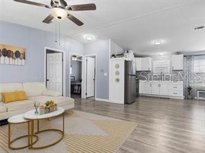 An open-concept living room and kitchen featuring light wood flooring and a ceiling fan — 4884 DUNCAN ROAD, PUNTA GORDA, FL
