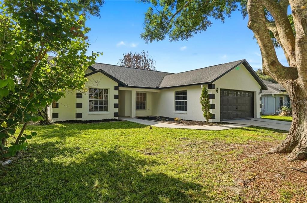 A single-story house with a white exterior, dark trim, and a two-car garage — 4209 RED BIRD AVENUE, ST CLOUD, FL