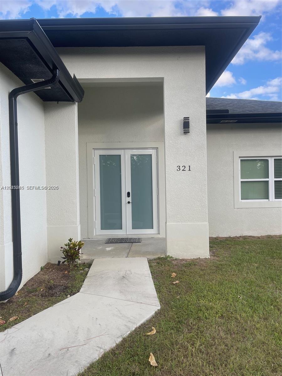 The exterior of a modern home features a double front door and a concrete walkway — 321 S Briggs # 0, Lehigh Acres FL 33974, LEHIGH ACRES, FL