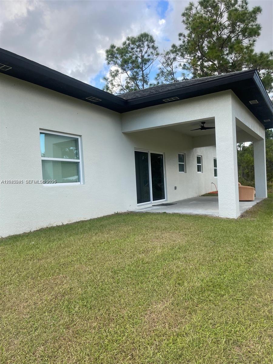 The exterior of a house features a covered patio, sliding glass doors, and a lawn — 321 S Briggs # 0, Lehigh Acres FL 33974, LEHIGH ACRES, FL