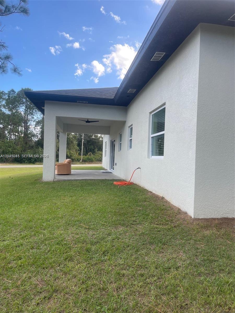 A side view of a house exterior featuring a covered patio and a grassy lawn — 321 S Briggs # 0, Lehigh Acres FL 33974, LEHIGH ACRES, FL