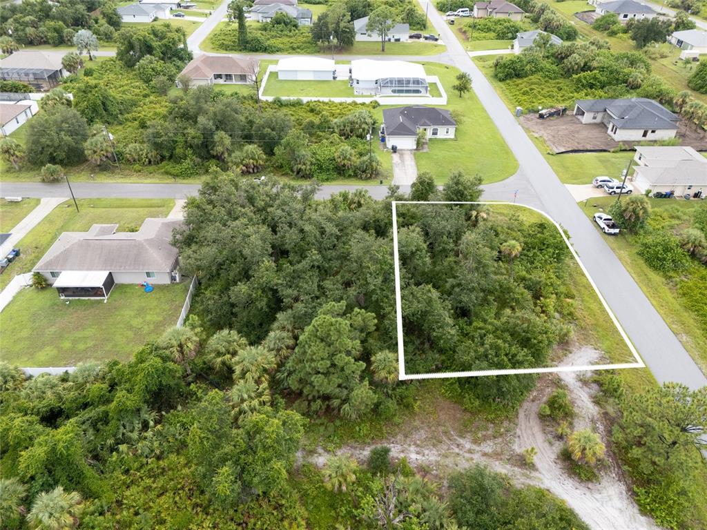An aerial view shows a vacant, wooded residential lot outlined in white next to a road — BRONCO LANE, NORTH PORT, FL