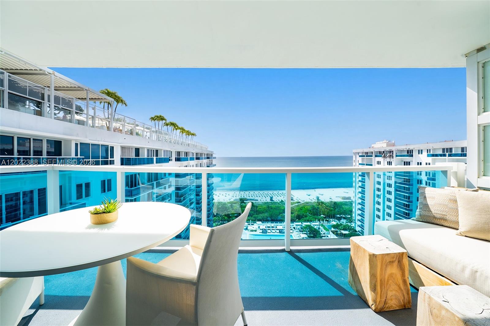 A balcony with a table, chairs, and sofa overlooks the ocean and nearby buildings — 102 24th St # 1718, Miami Beach FL 33139, MIAMI BEACH, FL