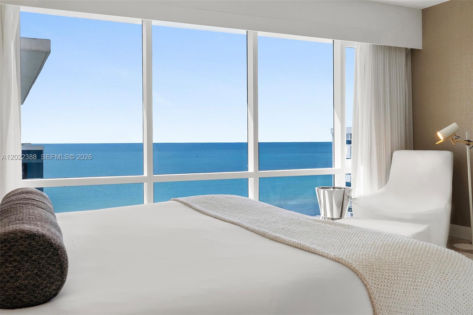 A bedroom features a large window with an ocean view and a white armchair — 102 24th St # 1718, Miami Beach FL 33139, MIAMI BEACH, FL