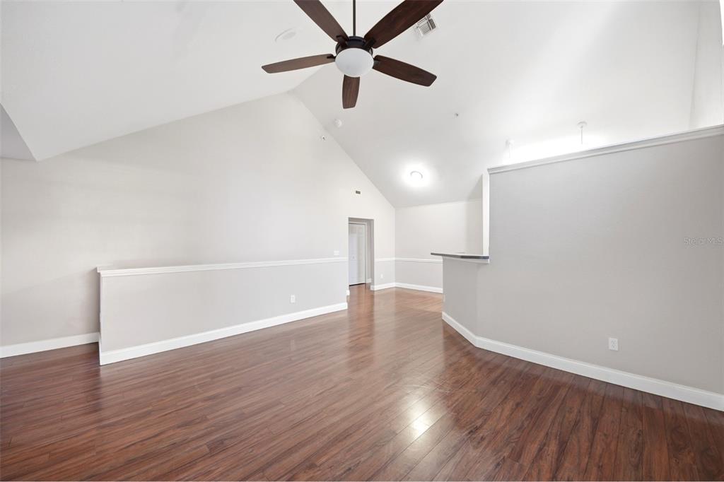 A spacious living area features vaulted ceilings, a ceiling fan, and dark wood-look flooring — 3364 WESTCHESTER SQUARE BOULEVARD UNIT 202, ORLANDO, FL