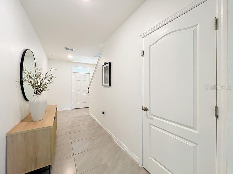 A bright entryway features light tile flooring, a wooden console table, and a white door — 1157 CASCADES AVENUE, DAVENPORT, FL