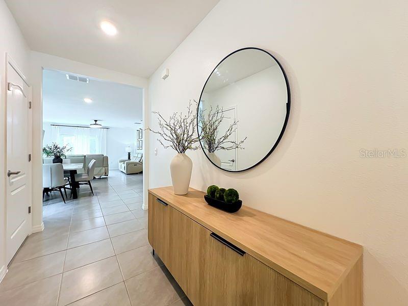 A hallway features a wooden console table, a round mirror, and a view into a living area — 1157 CASCADES AVENUE, DAVENPORT, FL