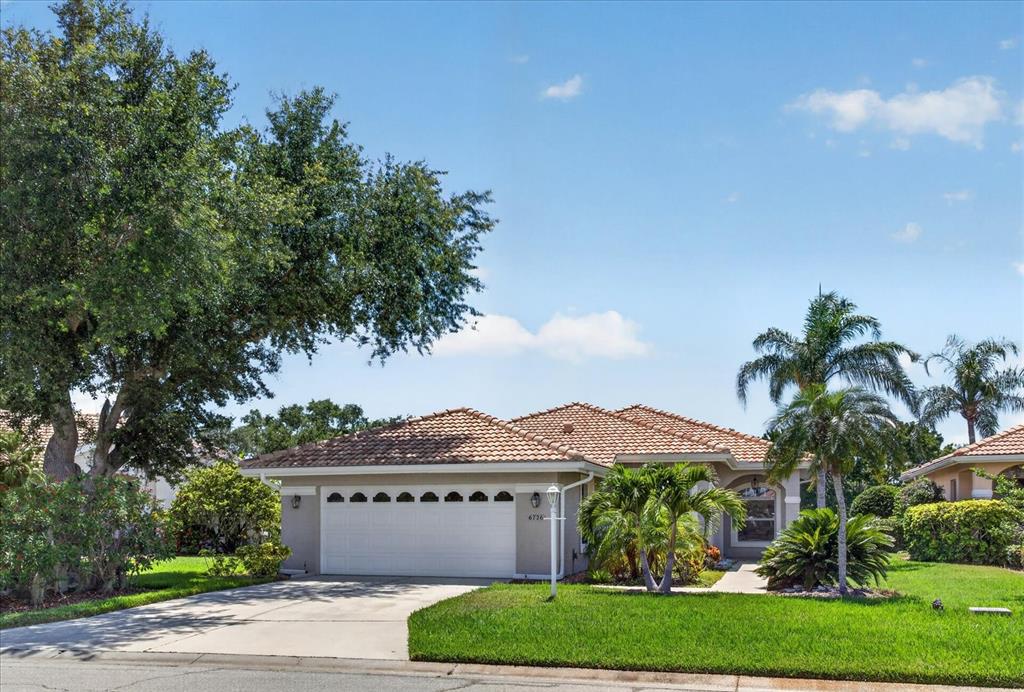 A single-story house with a tiled roof, a two-car garage, and palm trees in front — 6726 HICKORY HAMMOCK CIRCLE, BRADENTON, FL