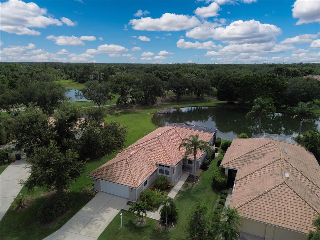 An aerial view shows a house with a tiled roof next to a pond — 6726 HICKORY HAMMOCK CIRCLE, BRADENTON, FL
