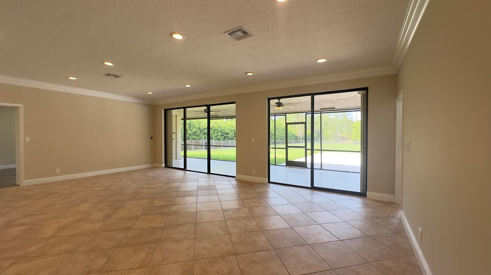 An empty room features beige walls, tile flooring, recessed lighting, and large sliding glass doors — 11330 Timberlodge Terrace, Boca Raton FL 33428, BOCA RATON, FL