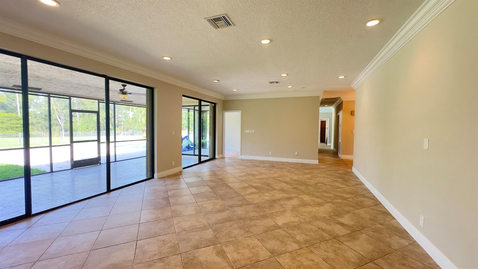 A bright living room features neutral furniture, a glass coffee table, and large sliding glass doors — 11330 Timberlodge Terrace, Boca Raton FL 33428, BOCA RATON, FL