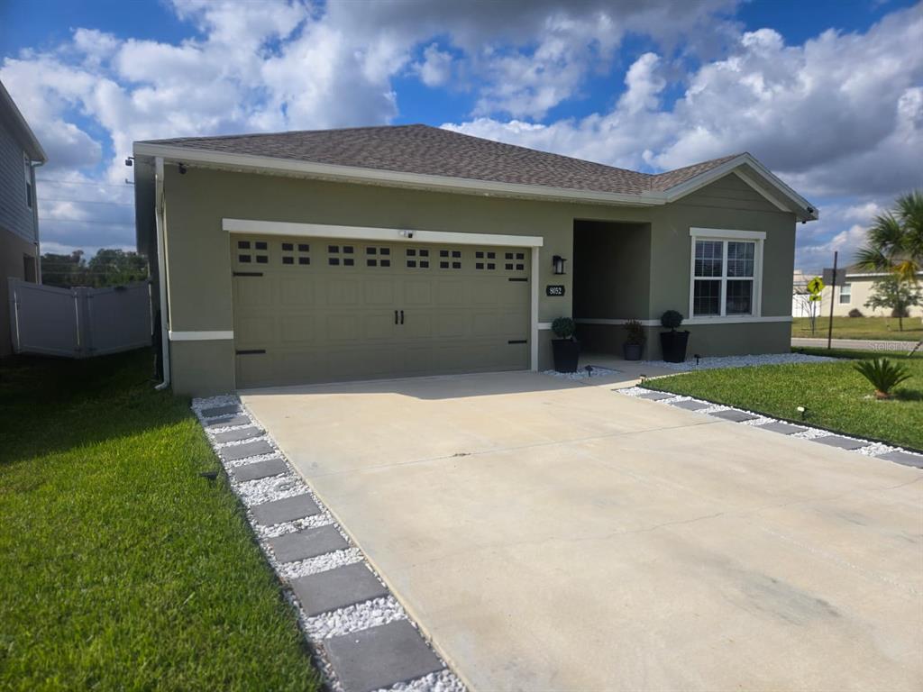 A single-story house with a tan stucco exterior, a two-car garage, and a concrete driveway — 8052 GREENWAY AVENUE, WESLEY CHAPEL, FL
