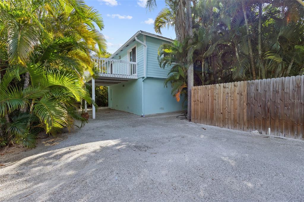 A light blue elevated house with a wooden deck and a gravel driveway — 315 SPRING AVENUE, ANNA MARIA, FL
