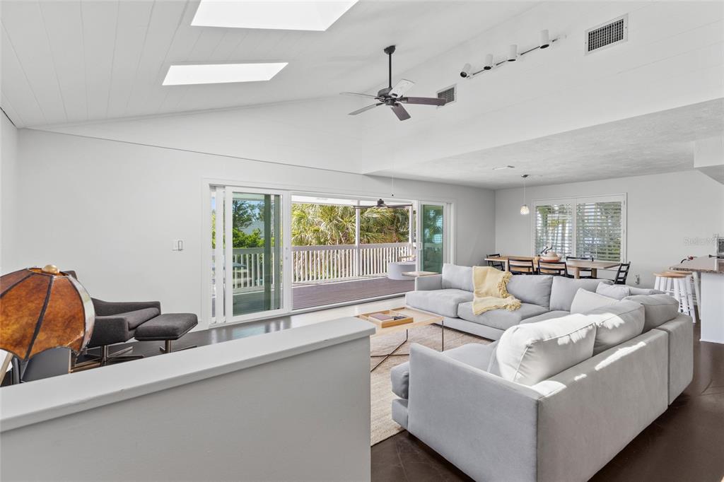A spacious living room features a vaulted ceiling, skylights, a large sectional, and sliding glass doors — 315 SPRING AVENUE, ANNA MARIA, FL