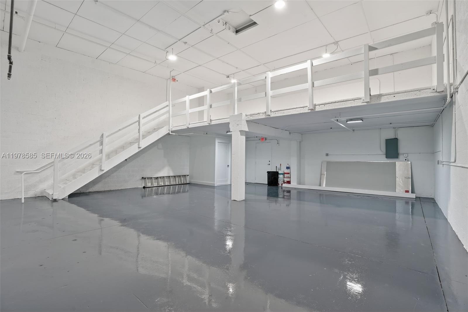 An industrial warehouse space features a gray epoxy floor, white walls, and a mezzanine level — 16300 SW 137th Ave # 119, Miami FL 33177, MIAMI, FL