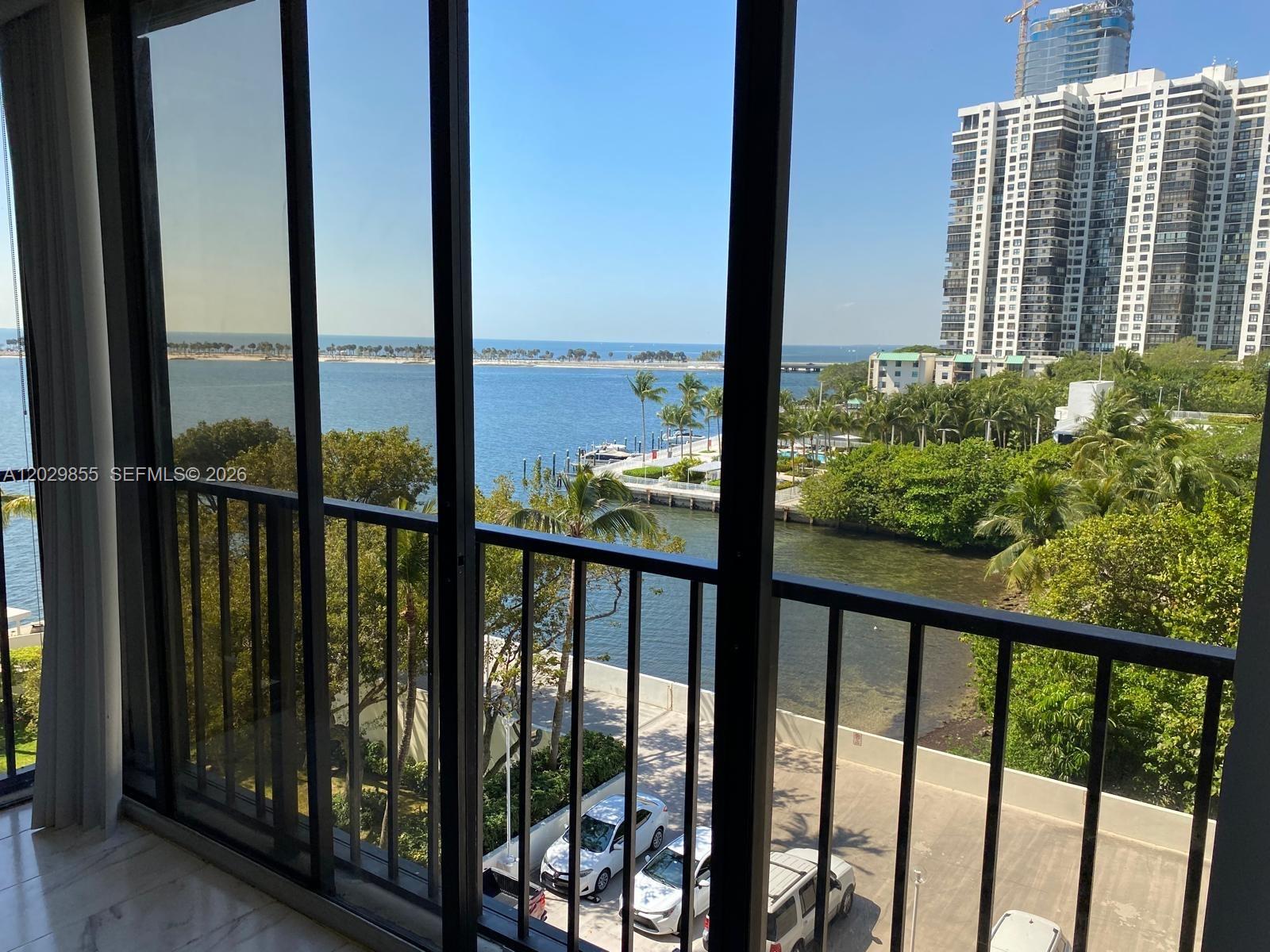 A view of the ocean and a high-rise building from a balcony with railings — 1925 Brickell Ave # D610, Miami FL 33129, MIAMI, FL