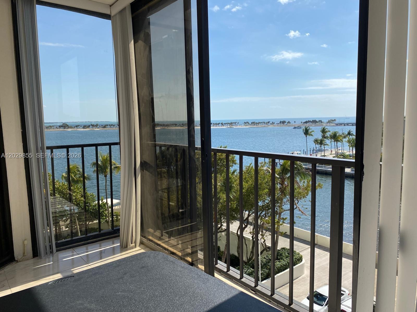 A view of the ocean and a marina from a balcony with a sliding door — 1925 Brickell Ave # D610, Miami FL 33129, MIAMI, FL