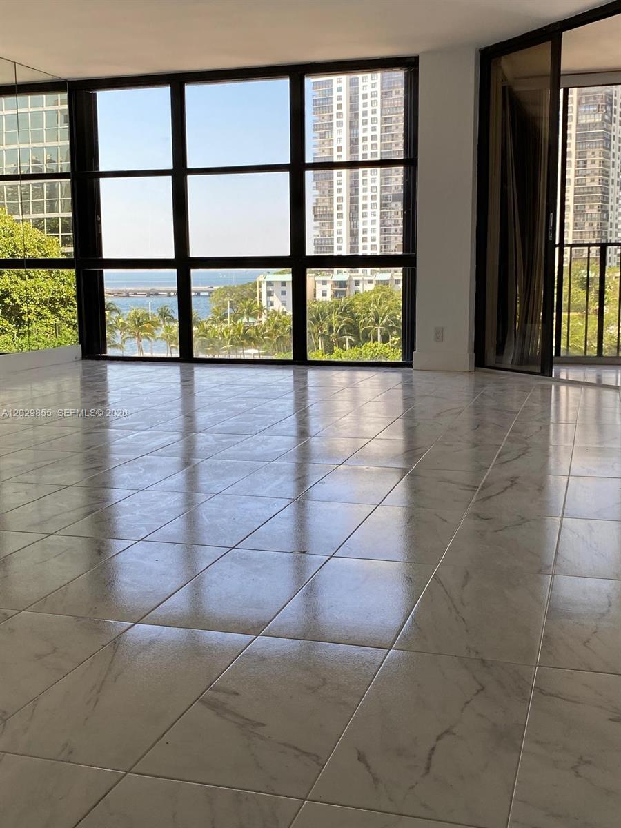 An empty room features large windows with water views and polished marble tile flooring — 1925 Brickell Ave # D610, Miami FL 33129, MIAMI, FL