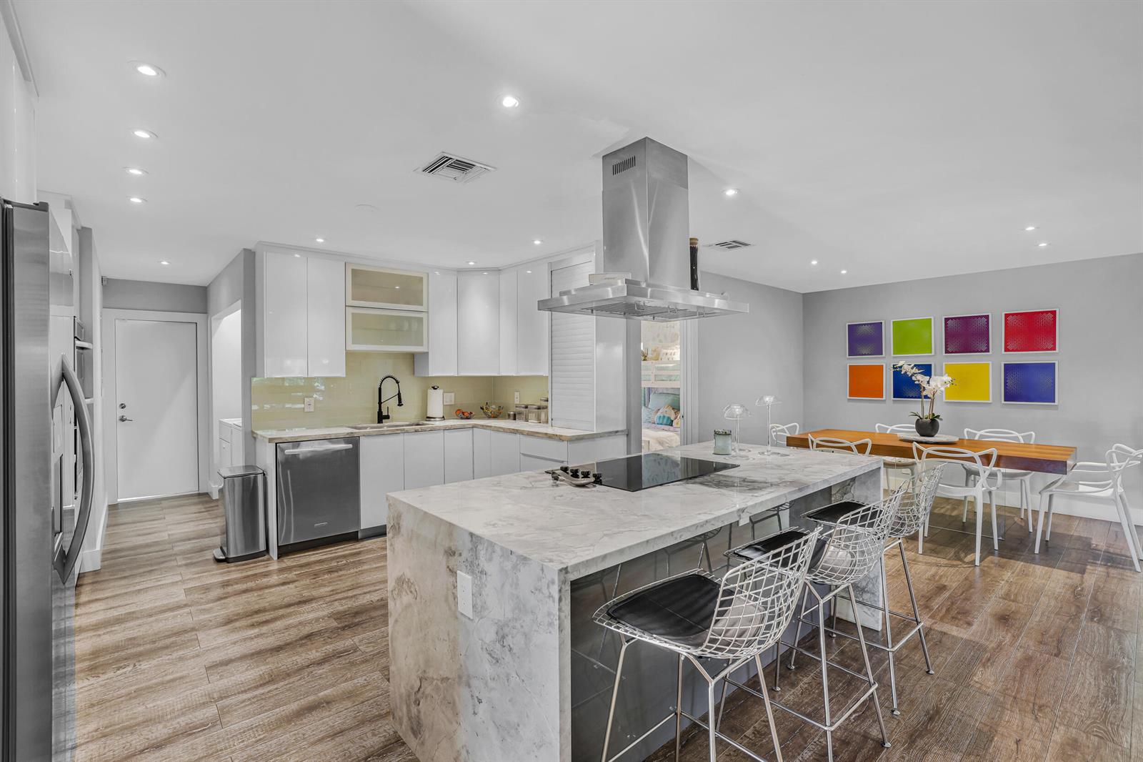A modern kitchen features a marble-topped island, stainless steel appliances, and an adjacent dining area — 908 Cypress Grove Drive, Pompano Beach FL 33069, POMPANO BEACH, FL