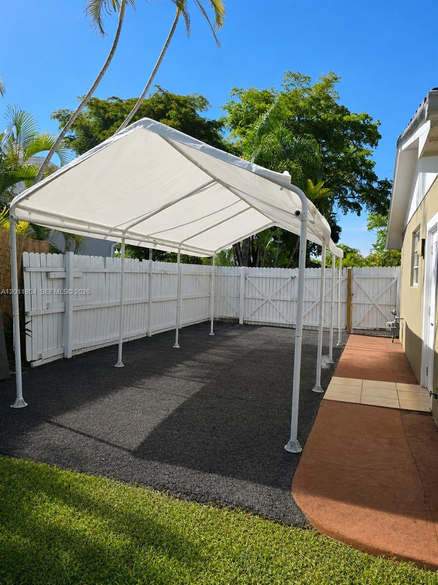 A white metal canopy structure stands over a paved patio area next to a house — 14020 SW 83rd St, Miami FL 33183, MIAMI, FL